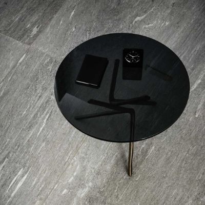 Ein schwarzer Beistelltisch steht auf einem Boden aus grauen Marazzi Keramik Platten